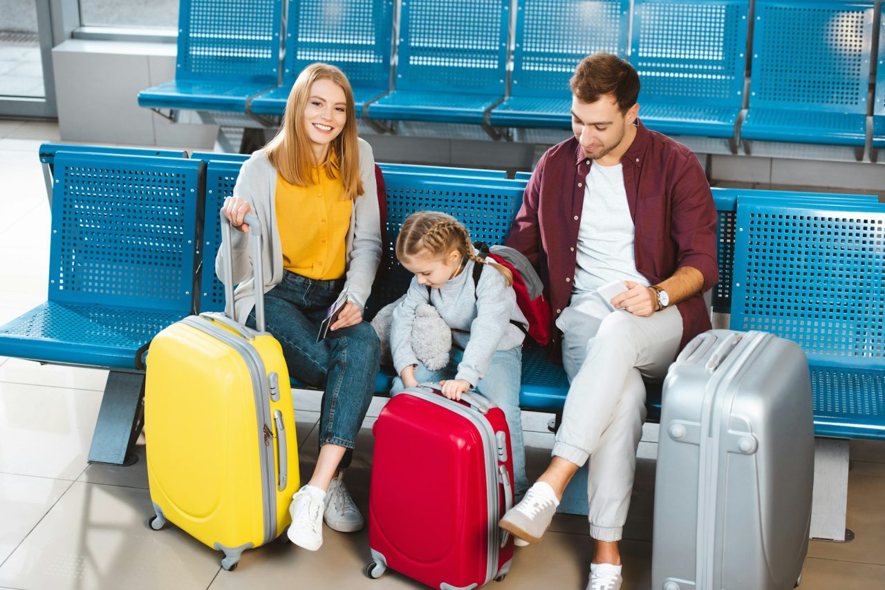 Happy Family Sitting Near Luggage And Smiling While Waiting For Flight In Airport 1 - Reliance Study Consultancy & Immigration