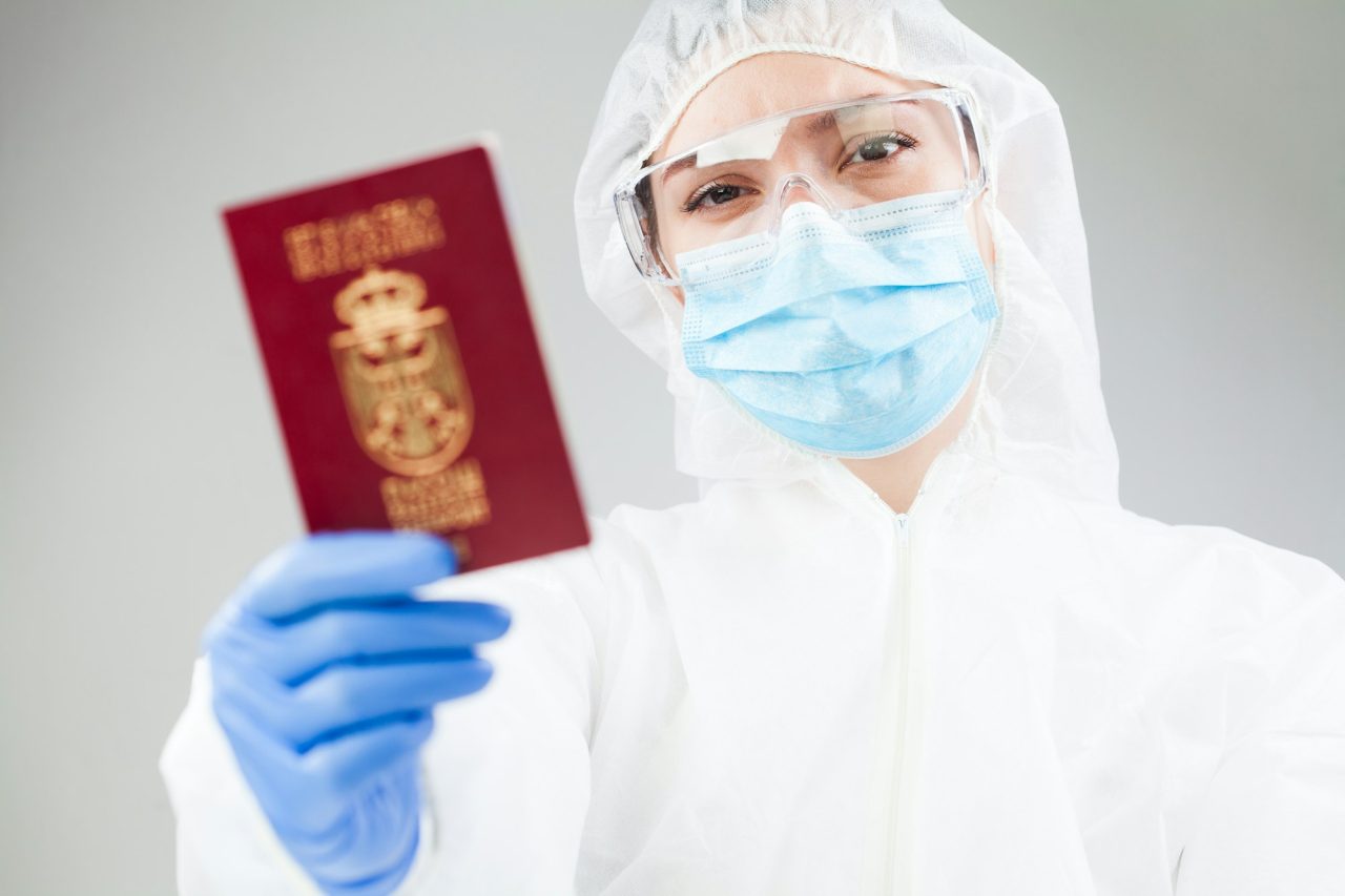 Medical Healthcare Worker In Full Personal Protective Equipment Holding Red Passport 1 - Reliance Study Consultancy & Immigration
